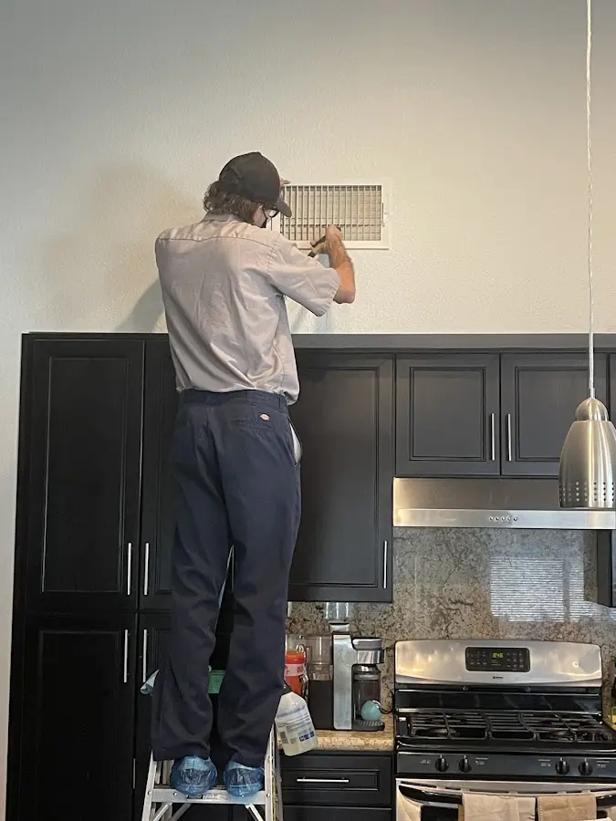 Technician inspecting an air vent during HVAC service in Wildomar